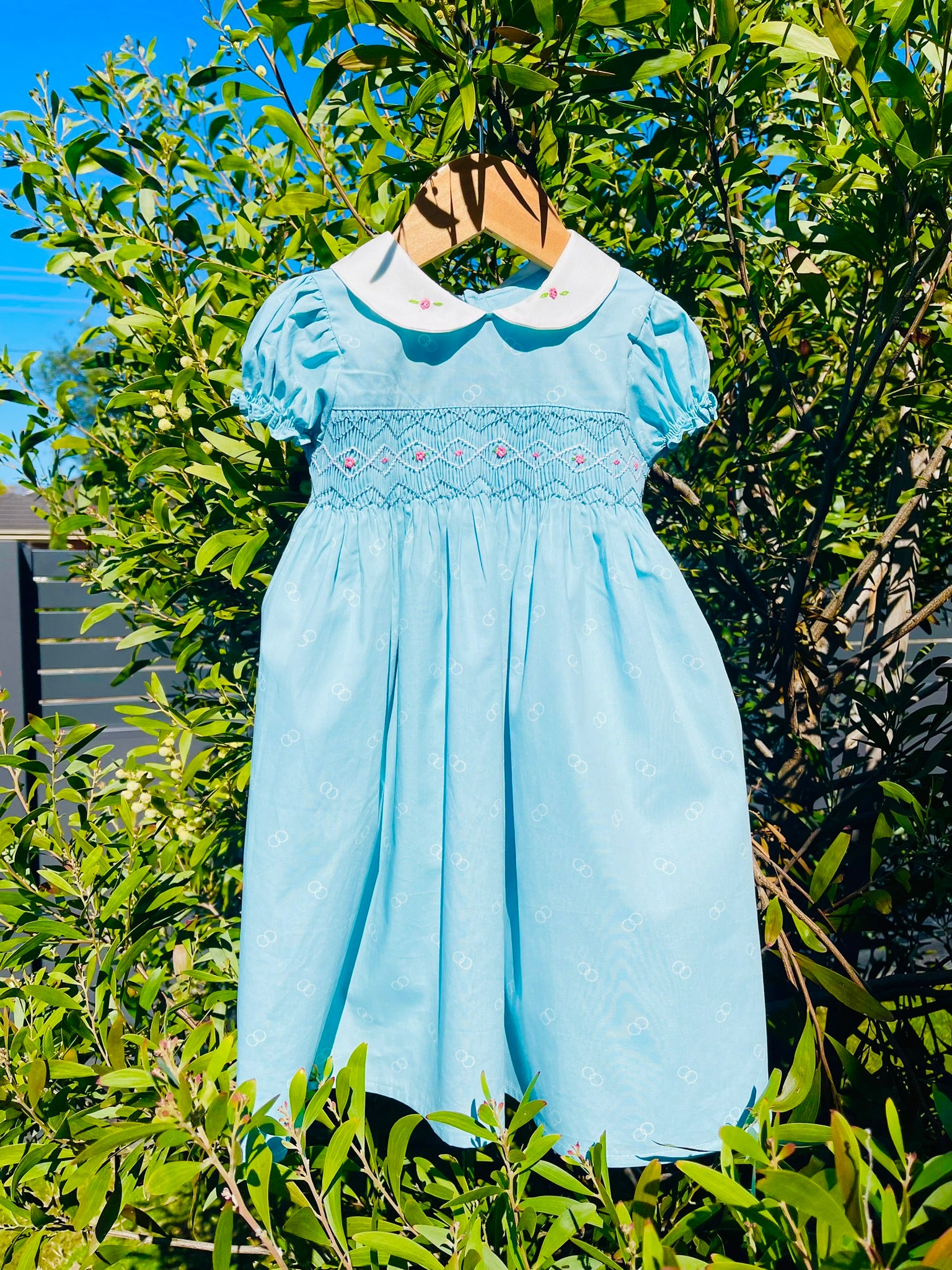 Blue hand smocked dress with pink rose bud embroidery and blue and white handsmocking