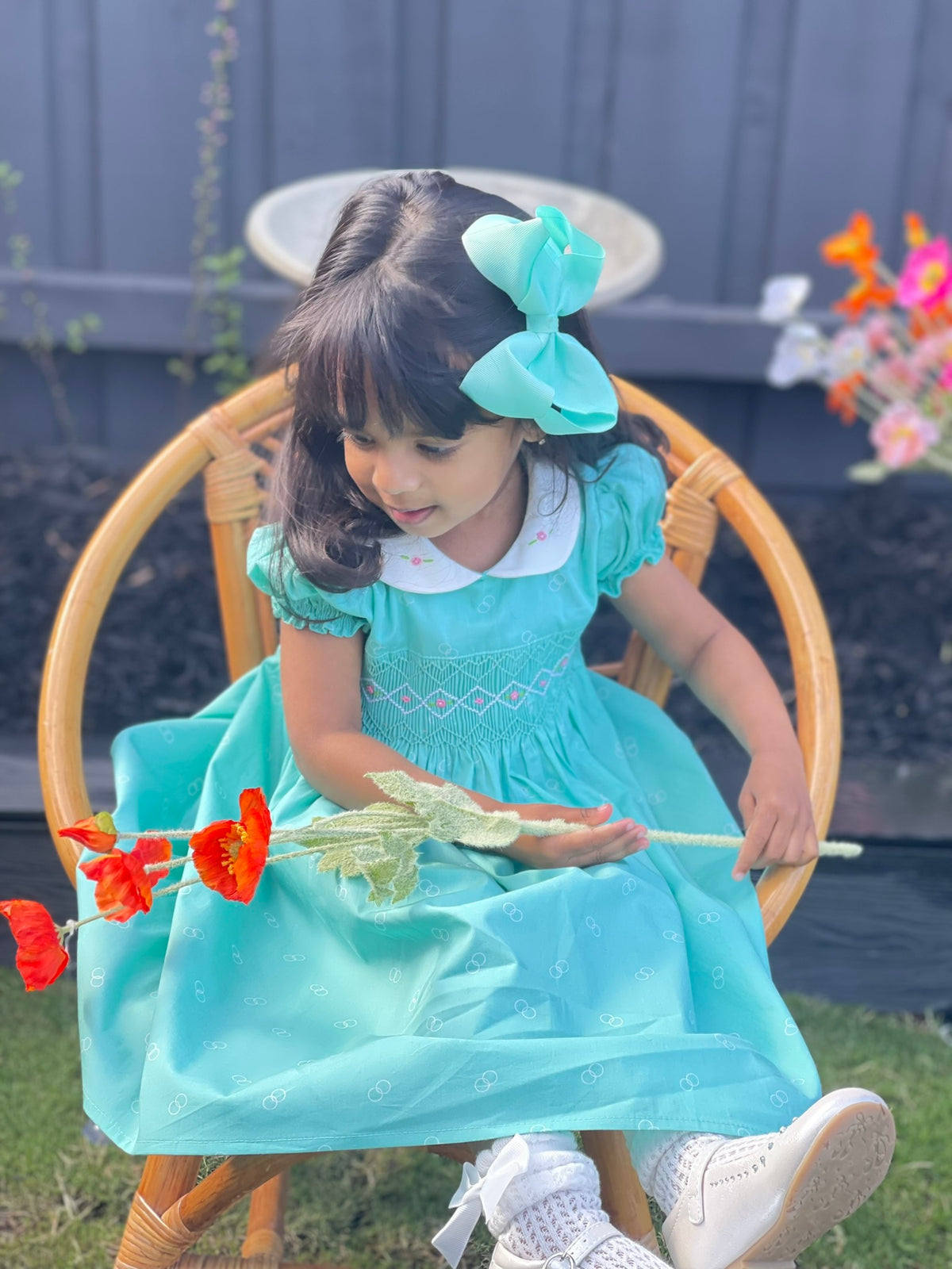 Girl Toddler wearing the Hand-smocked Emerald Rose Dress. Emerald green and white handsmocking with pink rose bud embrodiery. White collar with one pink rose bud embrodiery on each collar.Dress is a green colour.