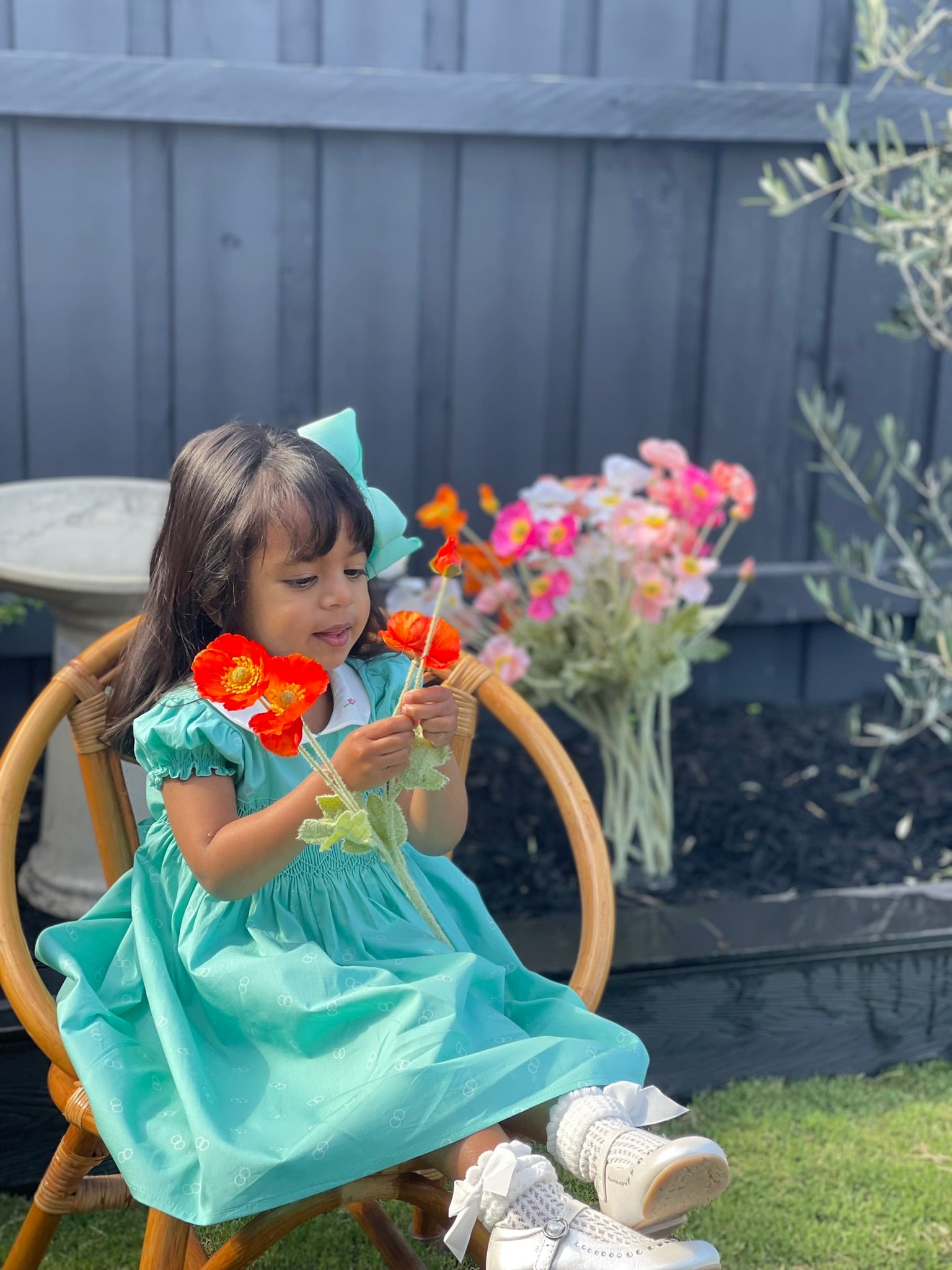 Girl Toddler wearing the Hand-smocked Emerald Rose Dress. Emerald green and white hand-smocking with pink rose bud embroidery. White collar with one pink rose bud embroidery on each collar. Dress is a green colour.