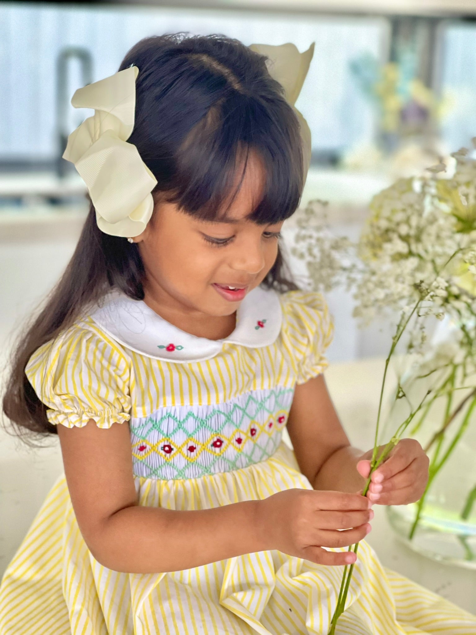 Girl wearing the marigold smock dress handsmocked yellow and white stripe dress 1