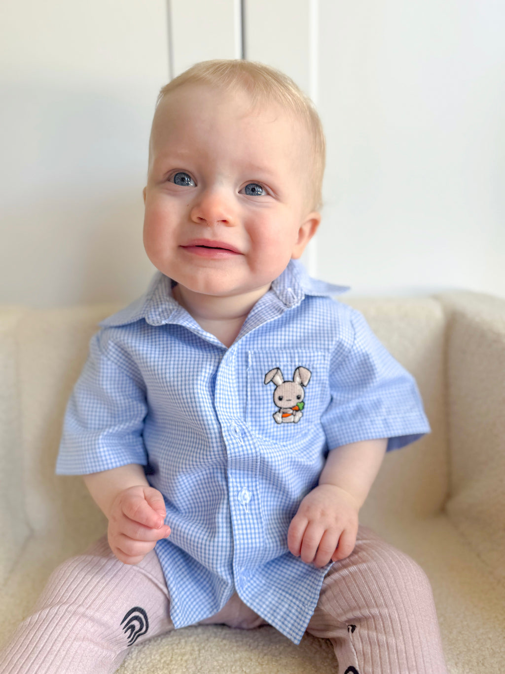 Baby wearing a blue checkered shirt with a cartoon character on a white background