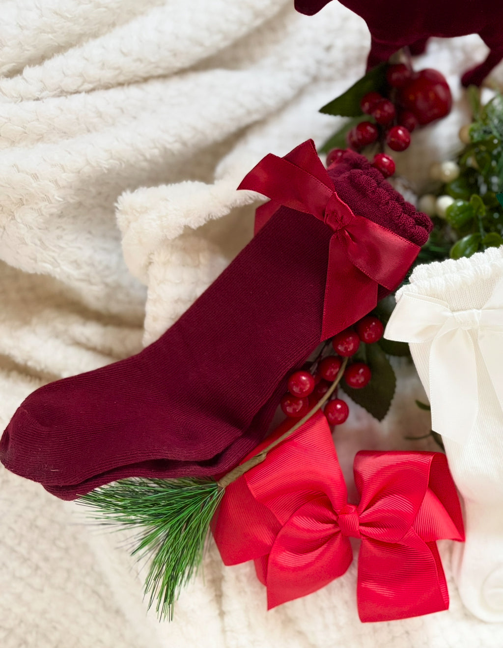 Red Christmas stocking with greenery and berries on a white background