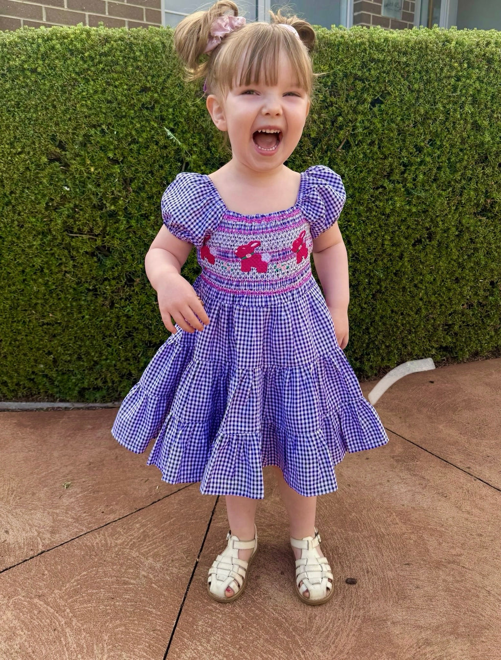 Girl wearing purple and white gingham smock dress with pink bunnies in the middle, 3 tier ruffle dress