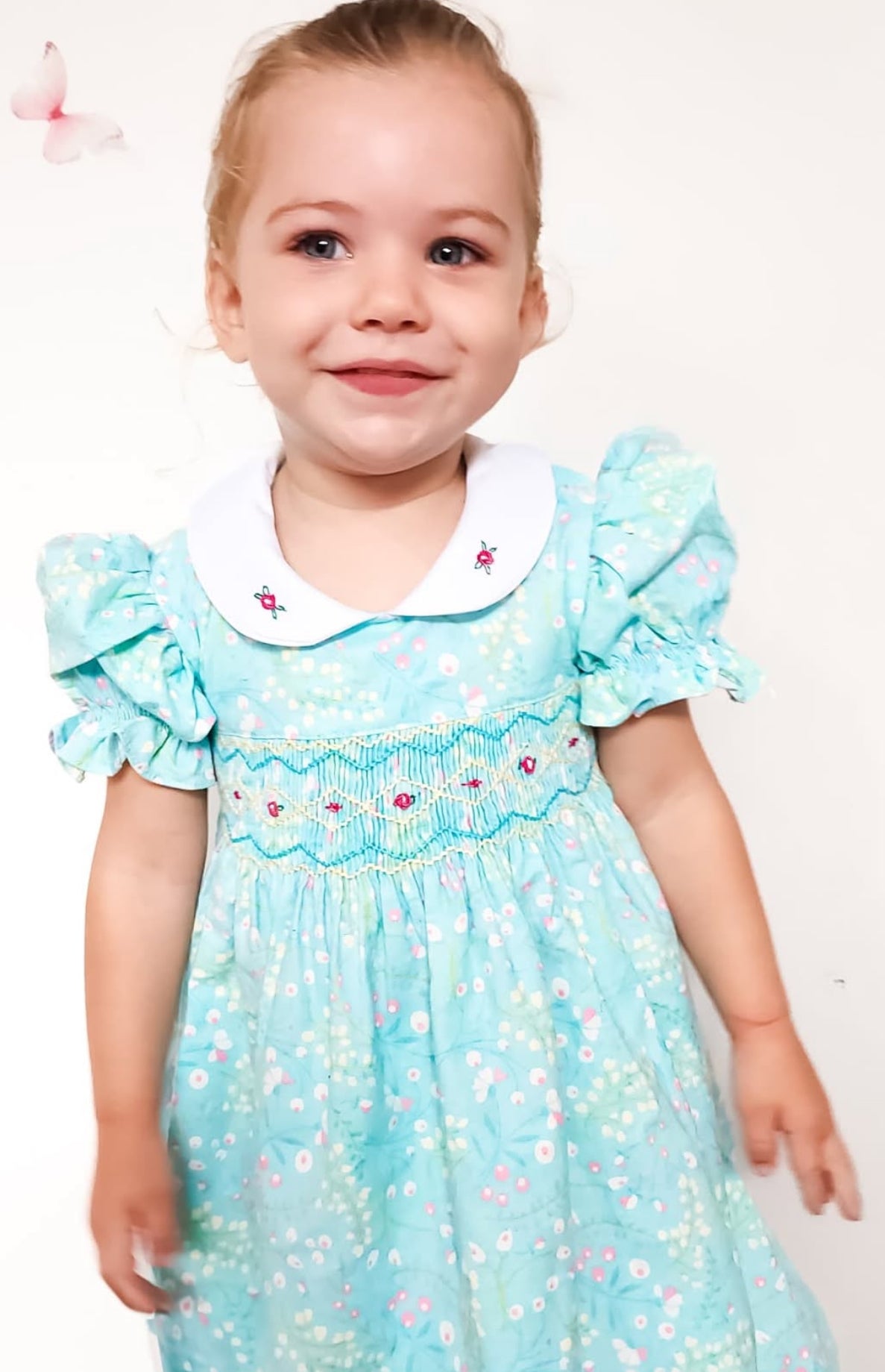 Turquoise seafoam colour smock dress with pink and white floral patterns, hand smocked bodice with ink rose bud embroidery