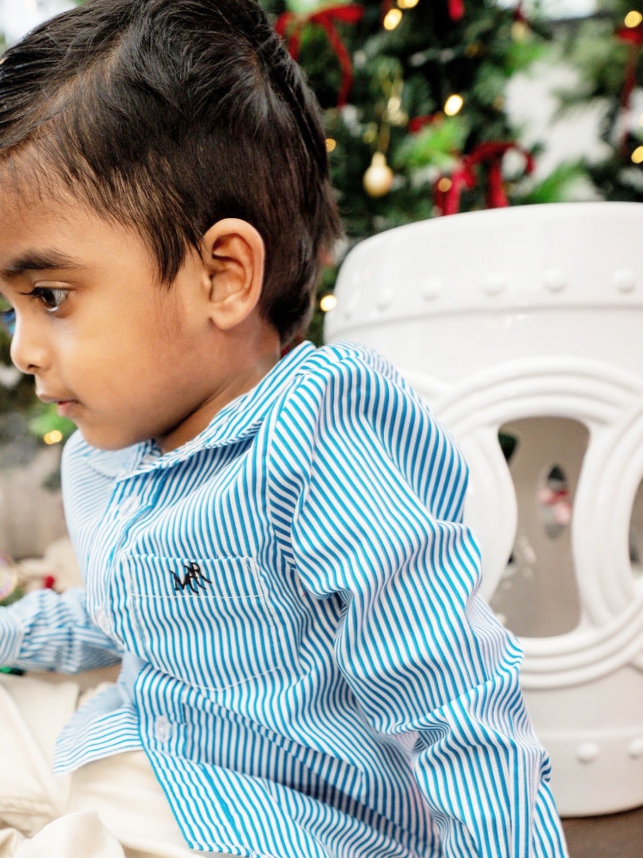 close up of a toddler boy wearing a white and blue shirt with MAR embroidery on the pocket