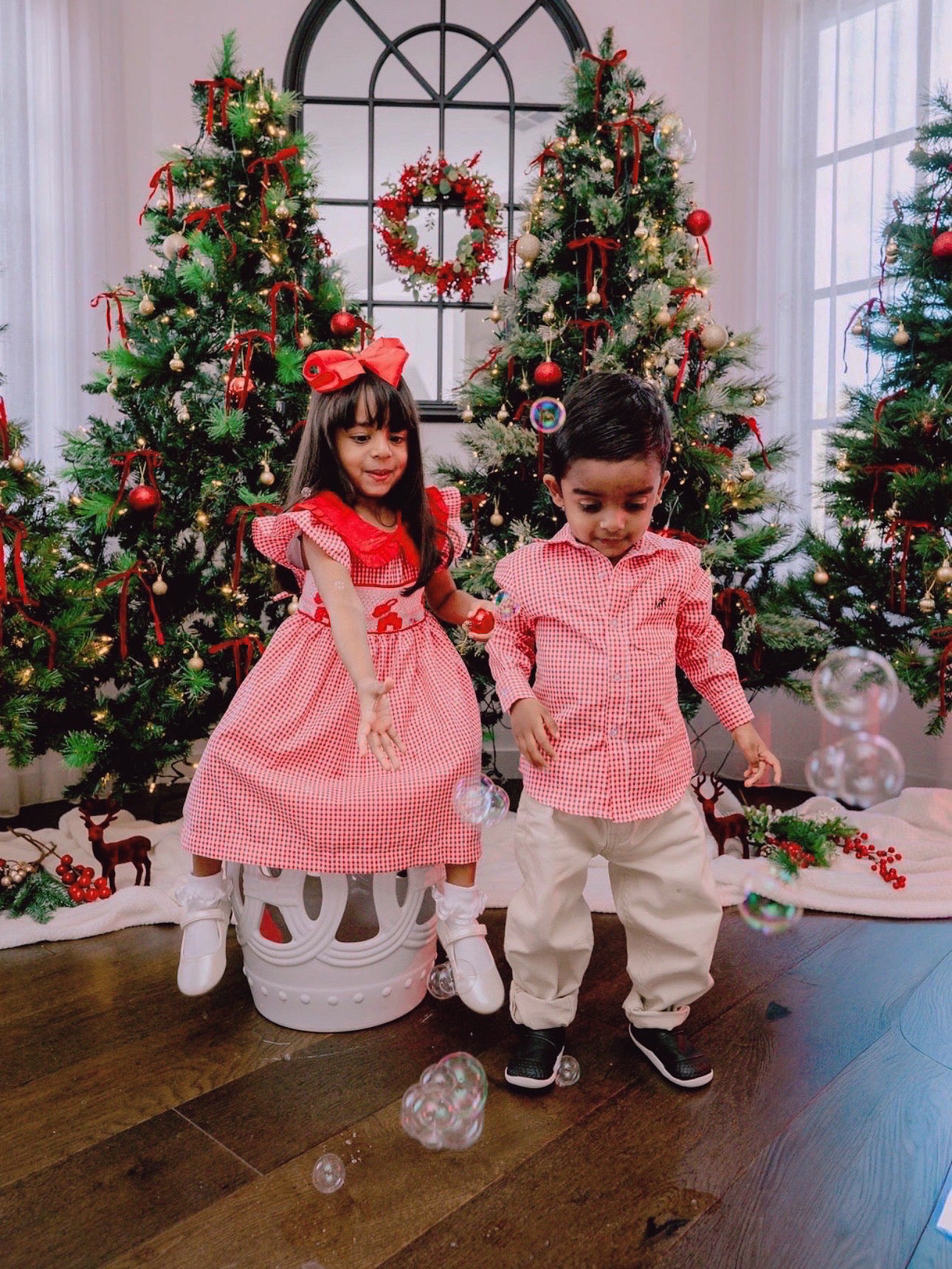 heritage red long sleeve boys shirt front with holly berry red dress for girls kids playing in front of Christmas tree in festive clothing